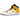 Air Jordan 1 Mid University Gold baskets vue sous angle avec cuir jaune et blanc emblématique, Swoosh noir et lacets blancs.