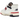 New Balance 550 Aime Leon Dore White Navy Red baskets vue sous angle avec tige en cuir blanc, logo bleu marine et détail rouge sur la semelle
